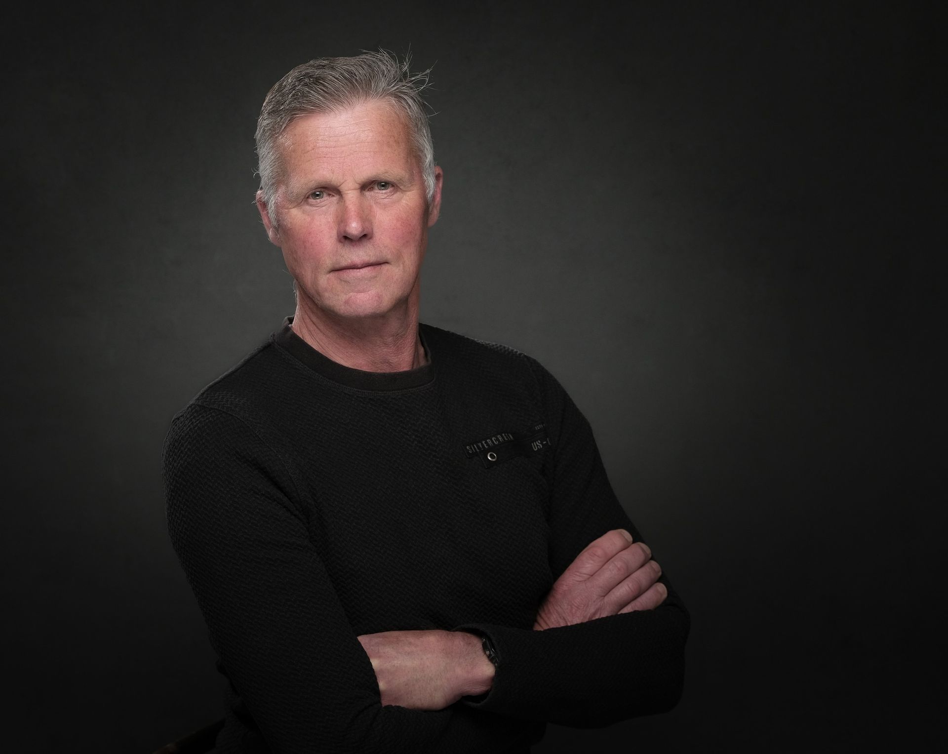 Een man in een zwarte trui staat met zijn armen over elkaar. Jan Spaans - Studio Spaans Fotograaf Dronten