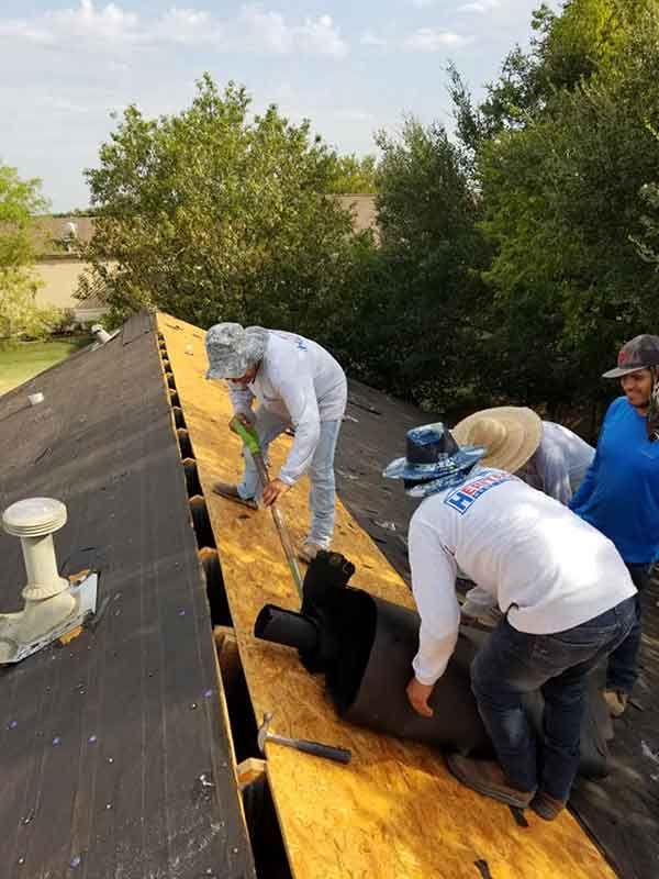 Roofers installing roofing material on a house, working on a sunny day.
