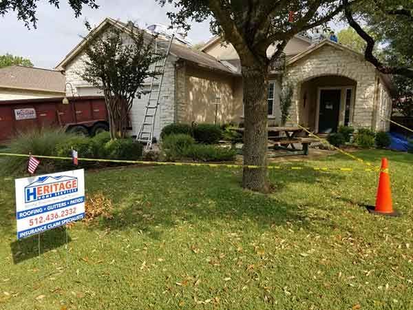 House with roofing work in progress. Dumpster and ladder visible. 