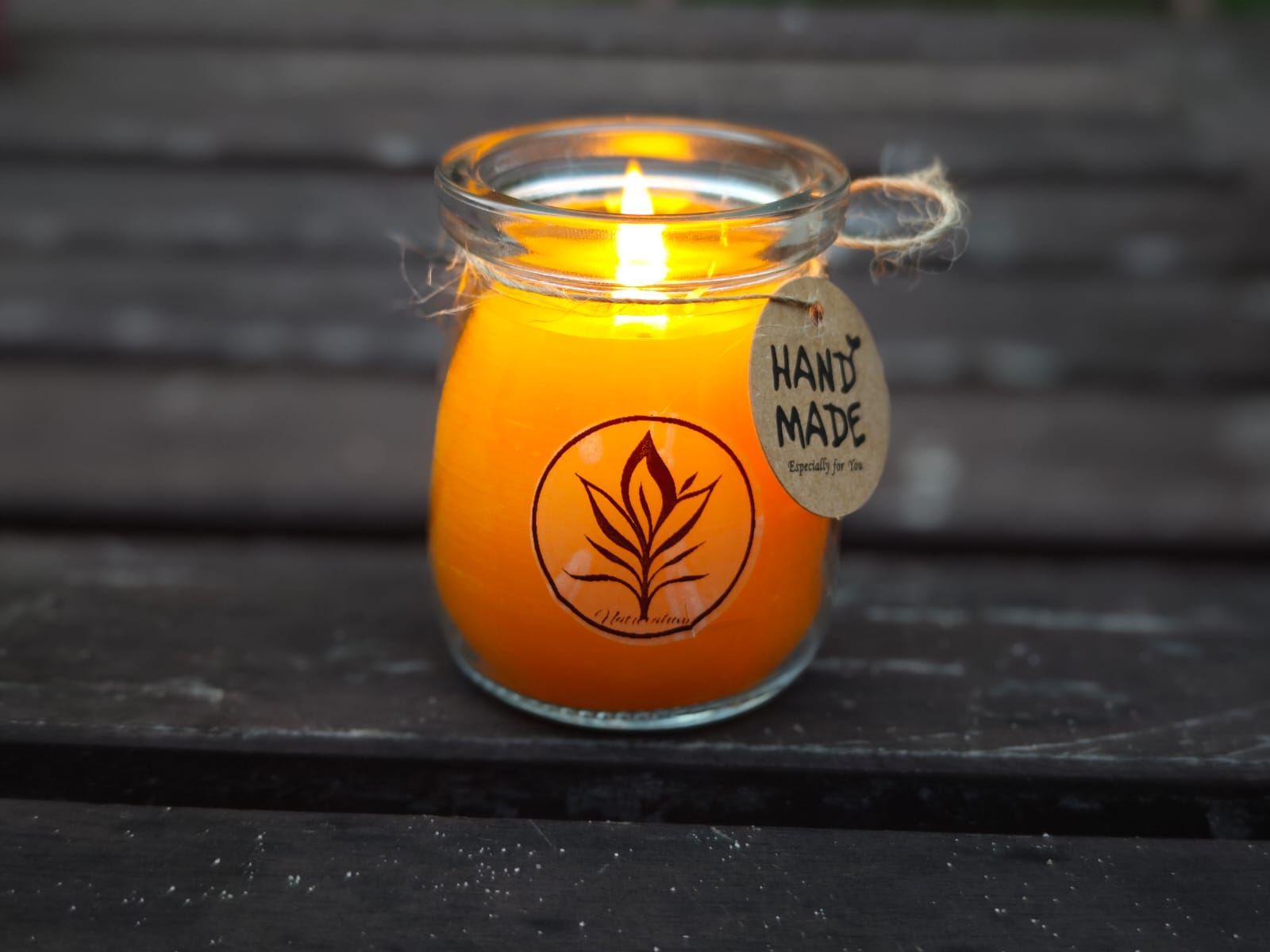 Brandende oranje kaars in een glazen pot met het label