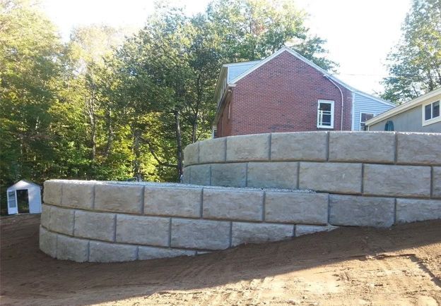 A brick wall with a brick house in the background