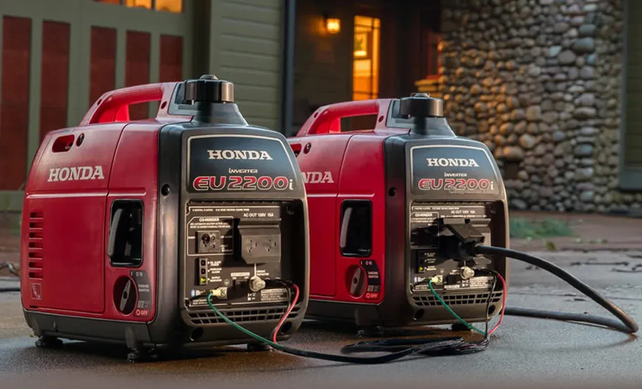 Two honda generators are sitting next to each other on the side of the road.