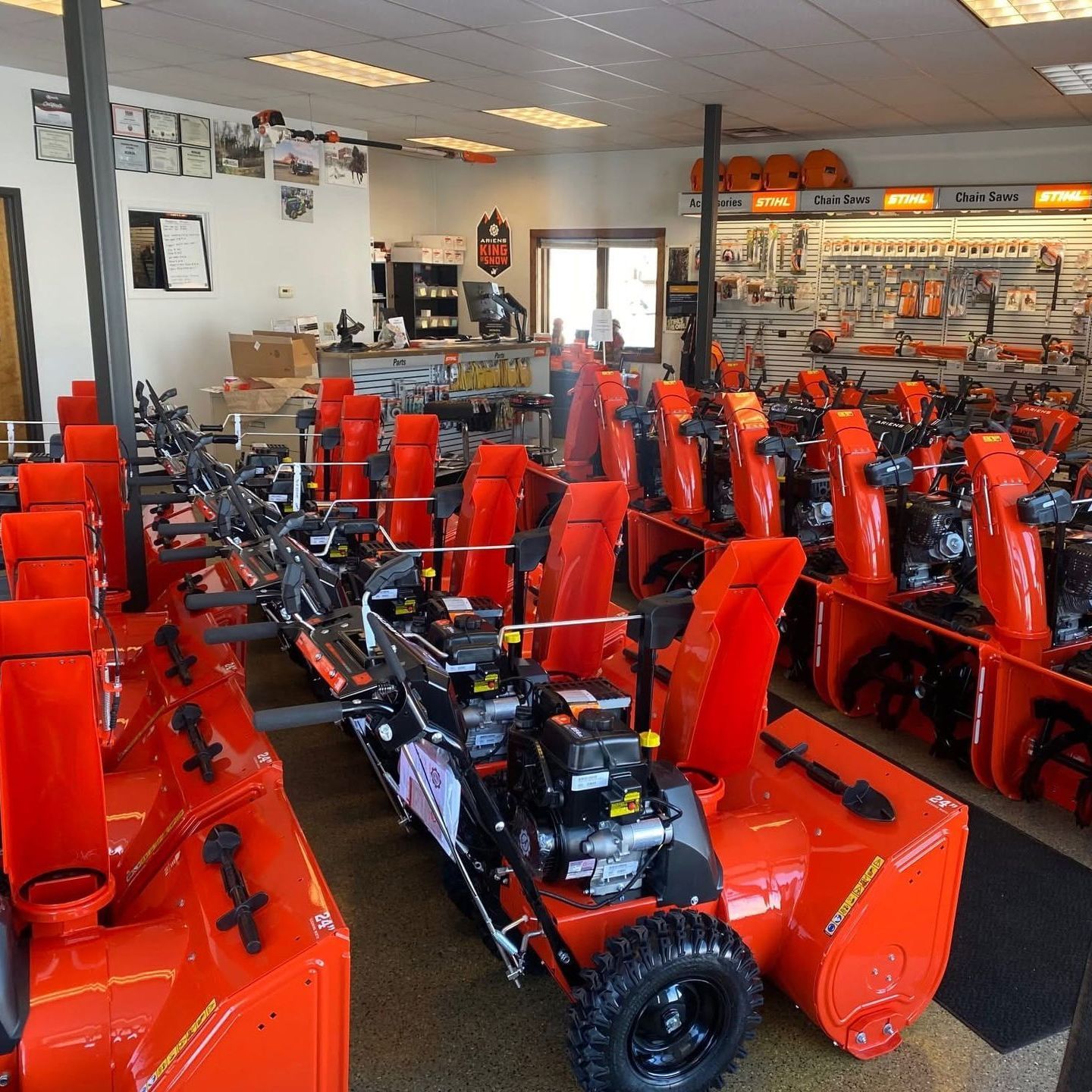 A row of orange snow blowers in a store