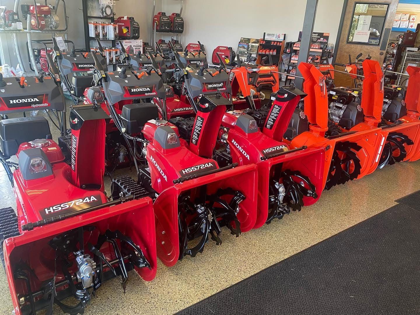 A row of snow blowers are lined up in a showroom.