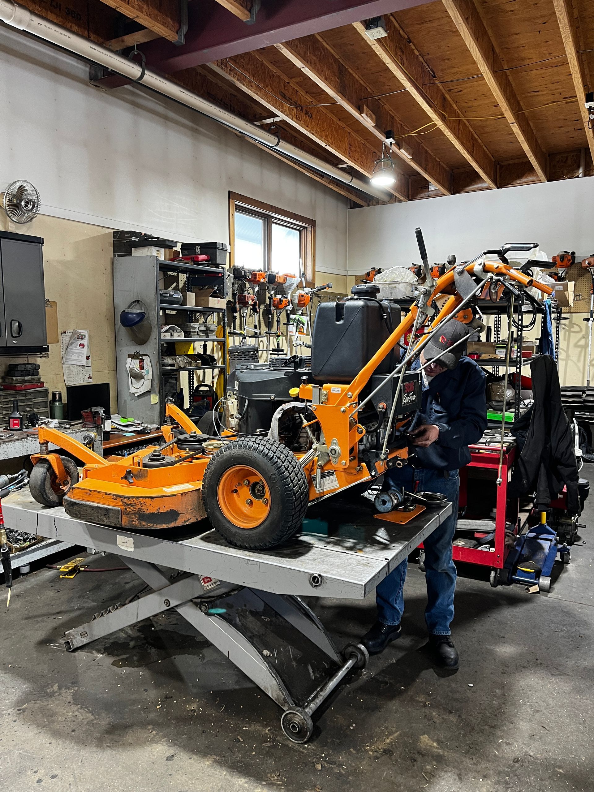 A man is working on a lawn mower in a garage.
