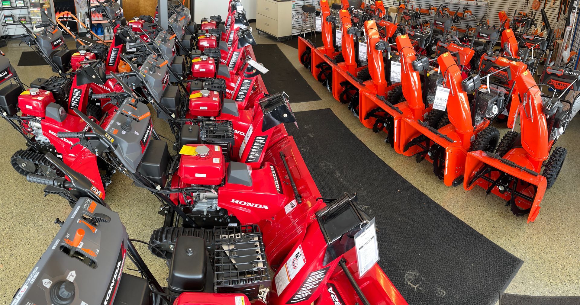A row of snow blowers are lined up in a showroom.