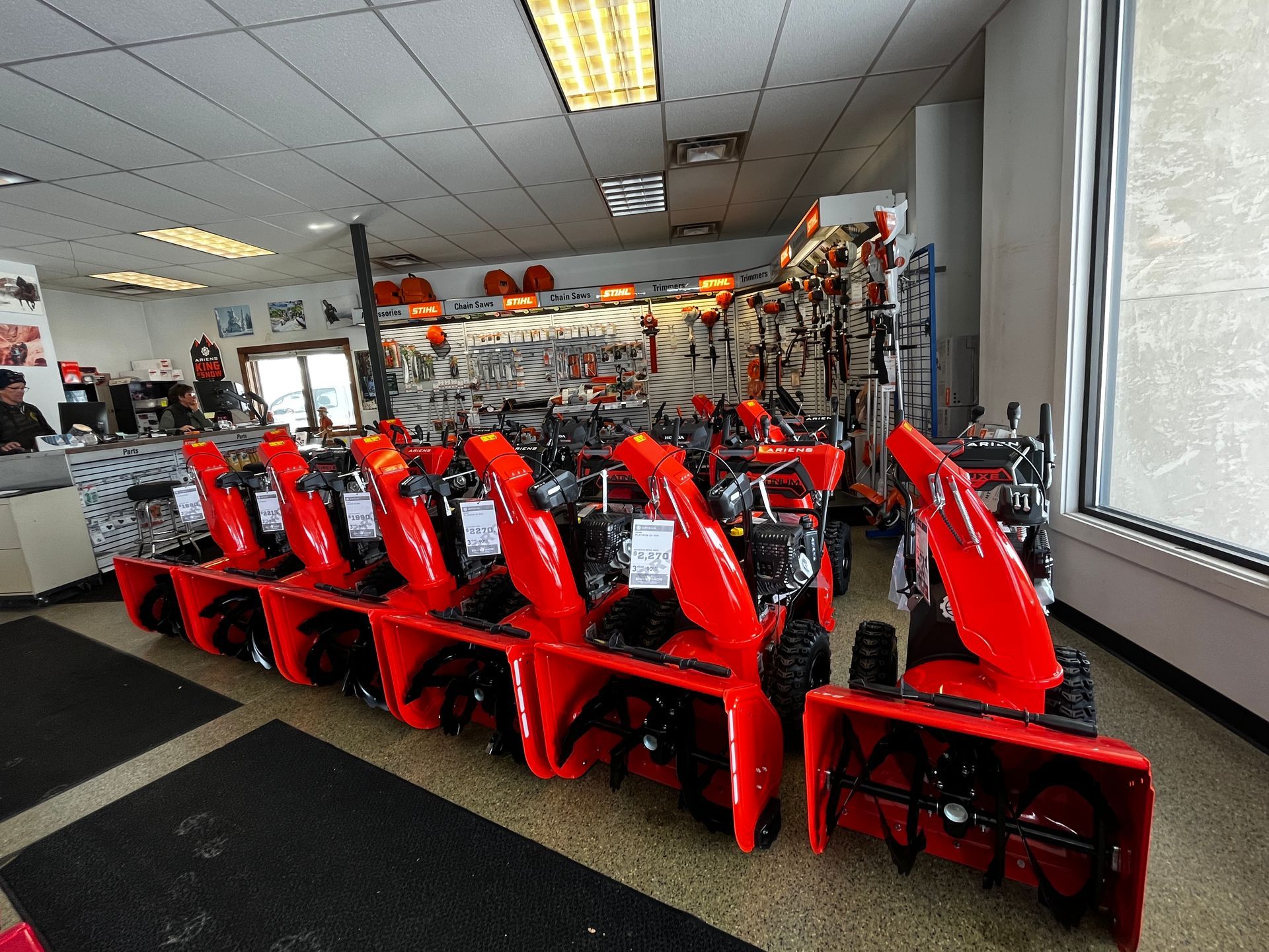 A row of snow blowers are lined up in a store.