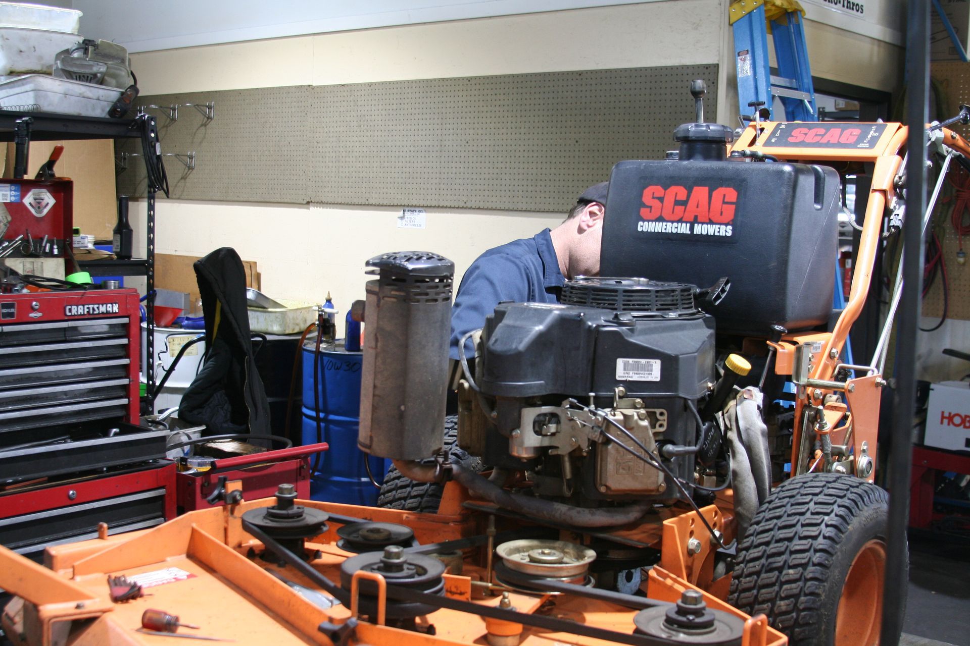 A man is working on a scag lawn mower in a garage