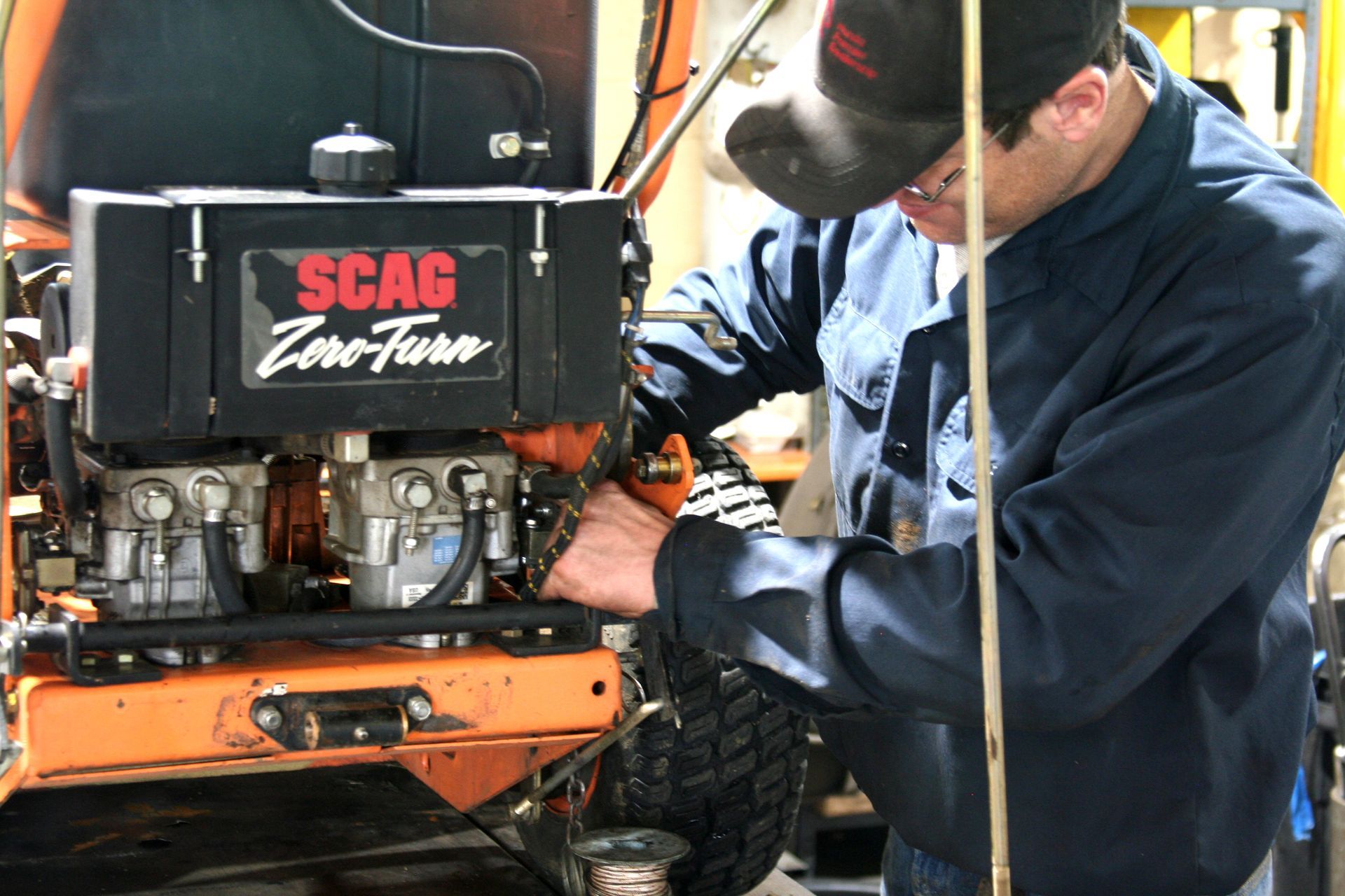 A man is working on a scag zero turn tractor
