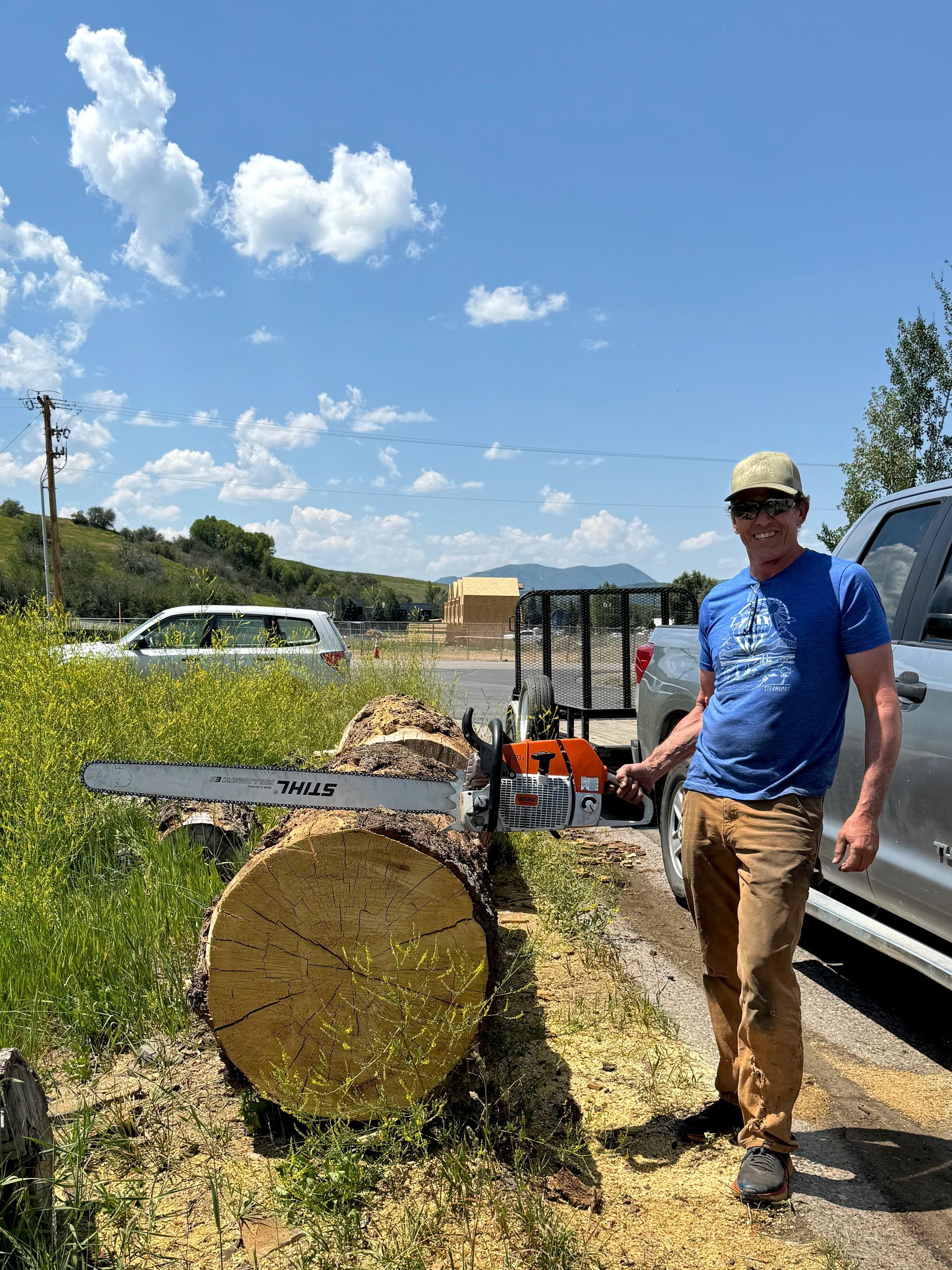 A man is standing next to a large log with a chainsaw.