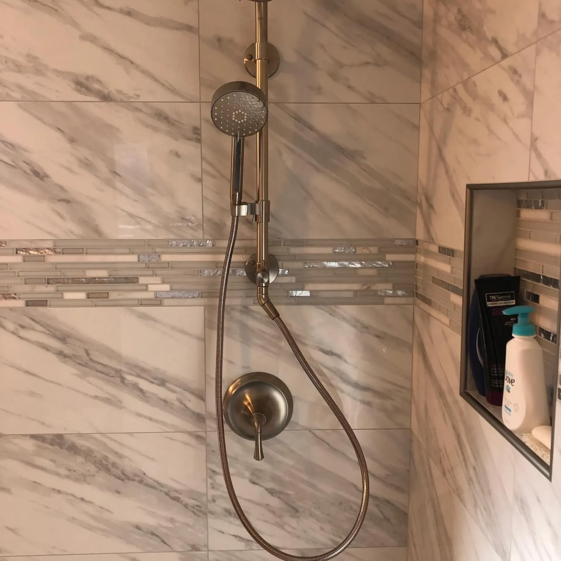 Ted & Bros Plumbing | shower with marble tiles and a shower head