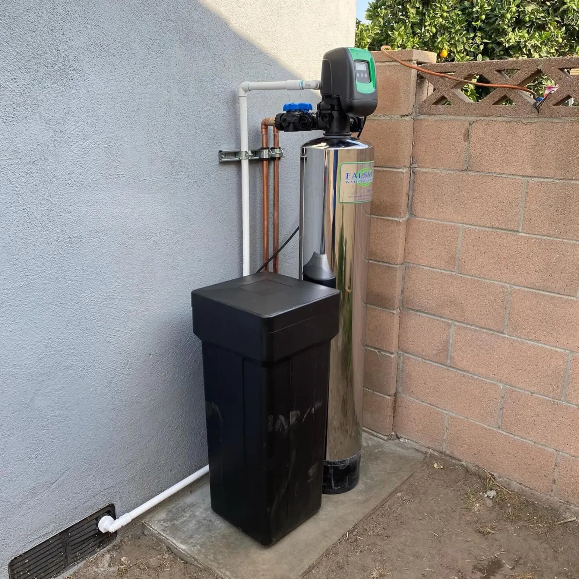 Ted & Bros Plumbing | water softener is sitting next to a brick wall.