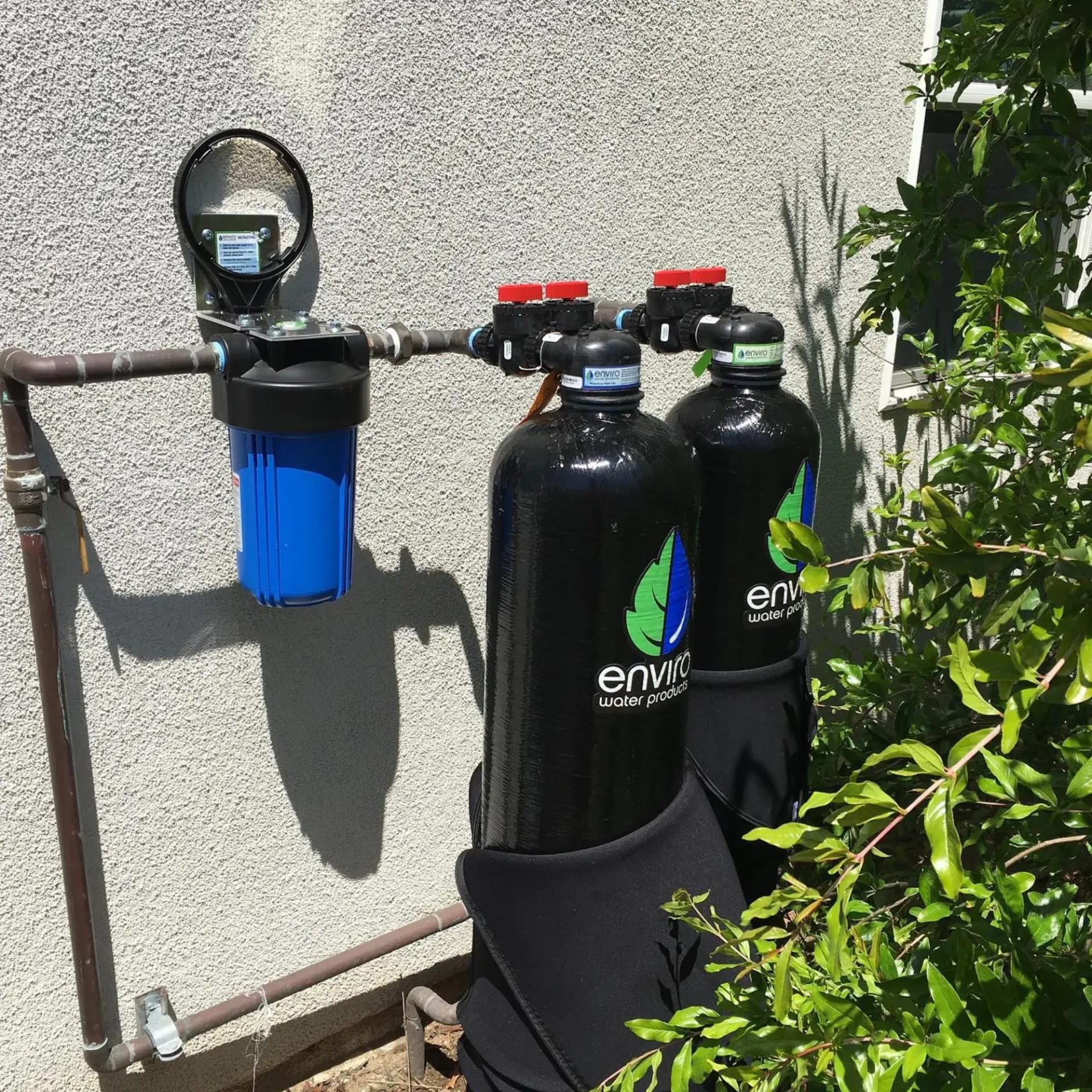 Ted & Bros Plumbing | Three water filters are attached to a pipe on the side of a building.