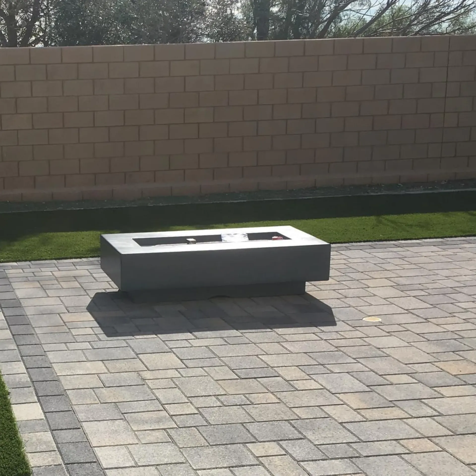 Ted & Bros Plumbing | fire pit sits on a brick patio in front of a brick wall
