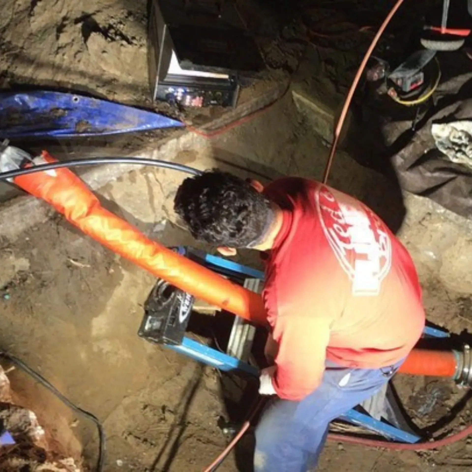 Ted & Bros Plumbing | man in a red shirt is working on a pipe