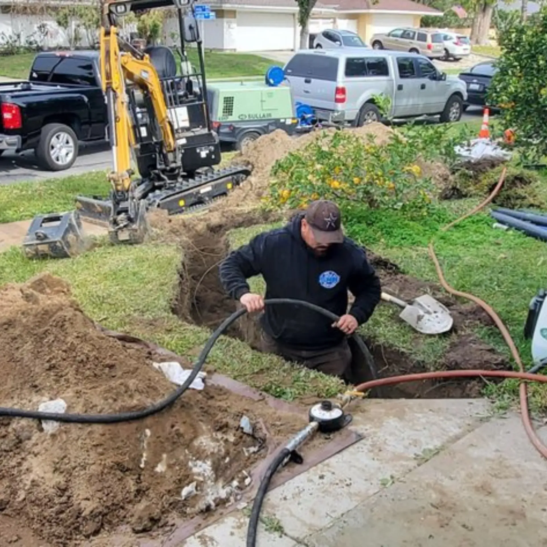 Ted & Bros Plumbing | man is digging a hole in the ground with a shovel and hose.