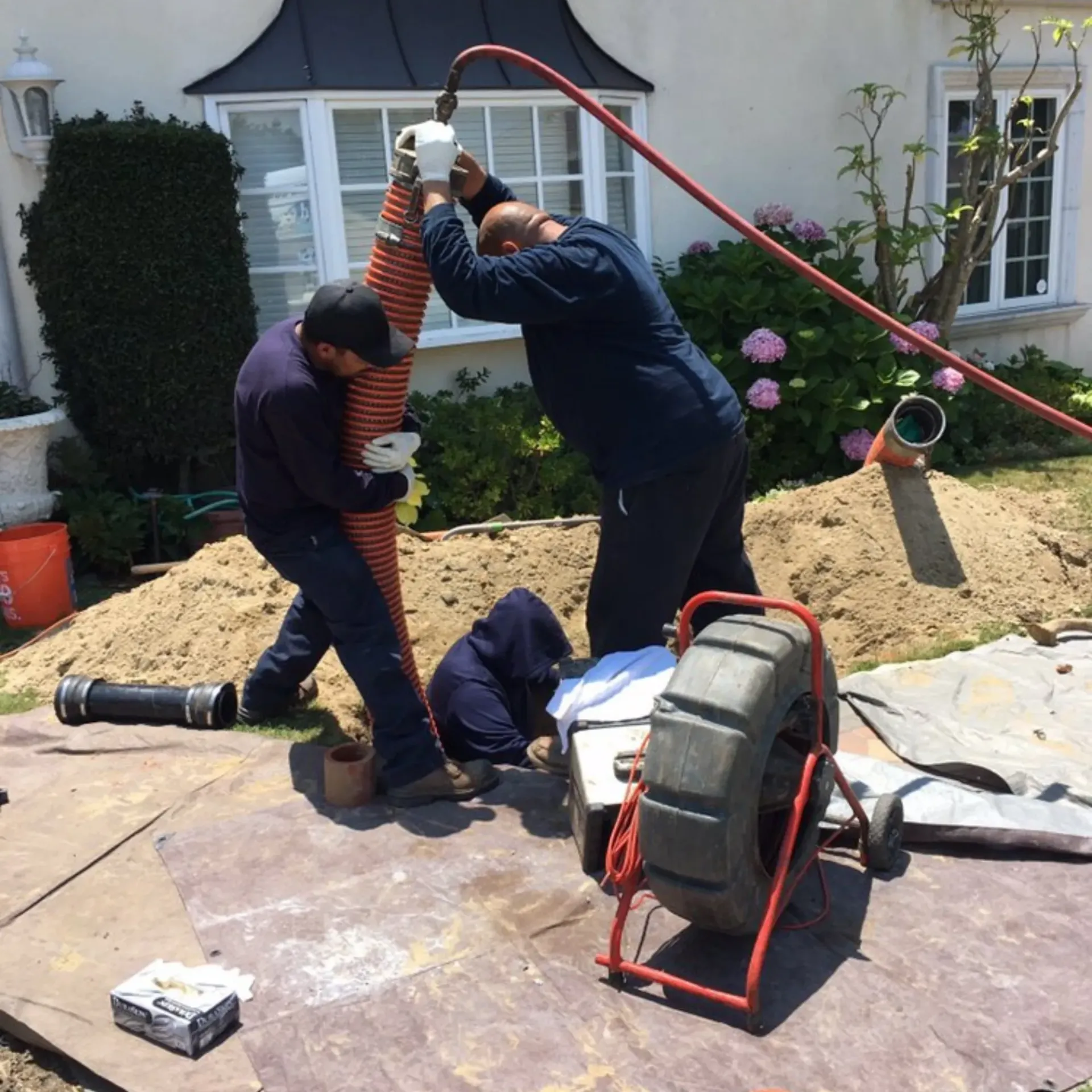 Ted & Bros Plumbing | group of men are working on a pipe outside of a house