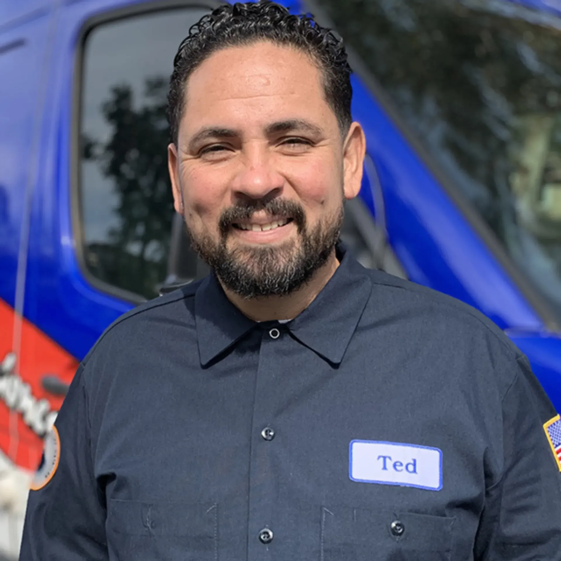 Ted & Bros Plumbing | man with a beard is smiling in front of a blue van.