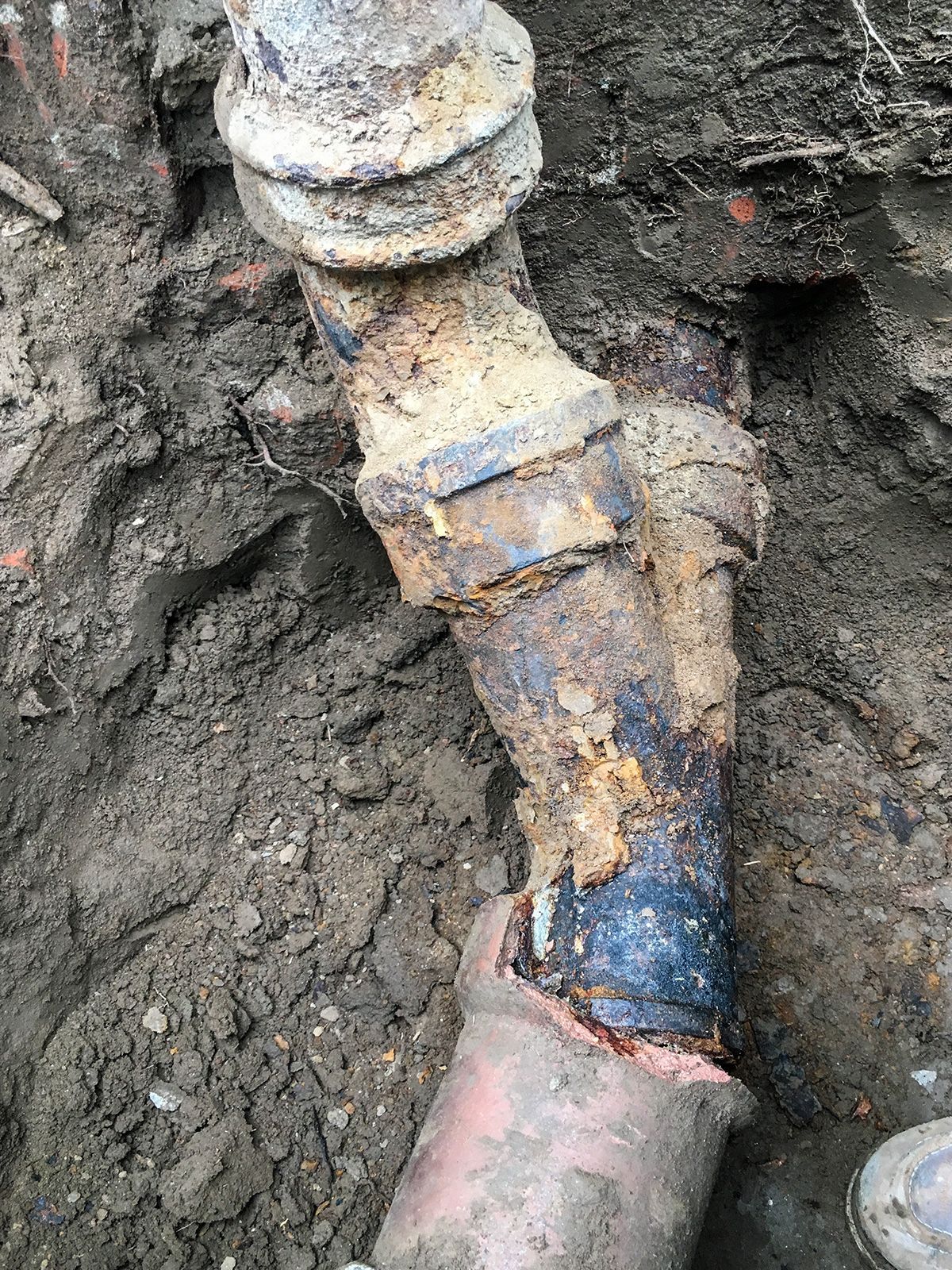 Ted & Bros Plumbing | close up of a rusty pipe in the dirt.