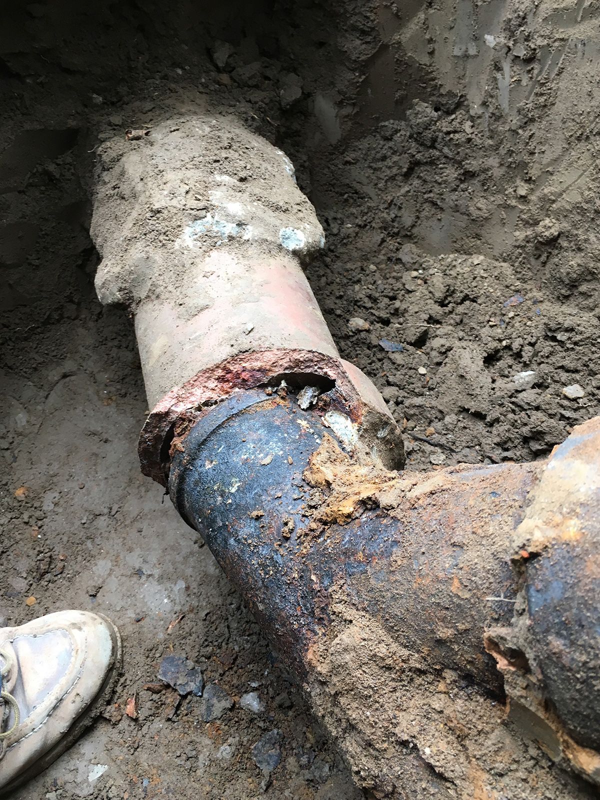 Ted & Bros Plumbing | close up of a rusty pipe in the dirt.