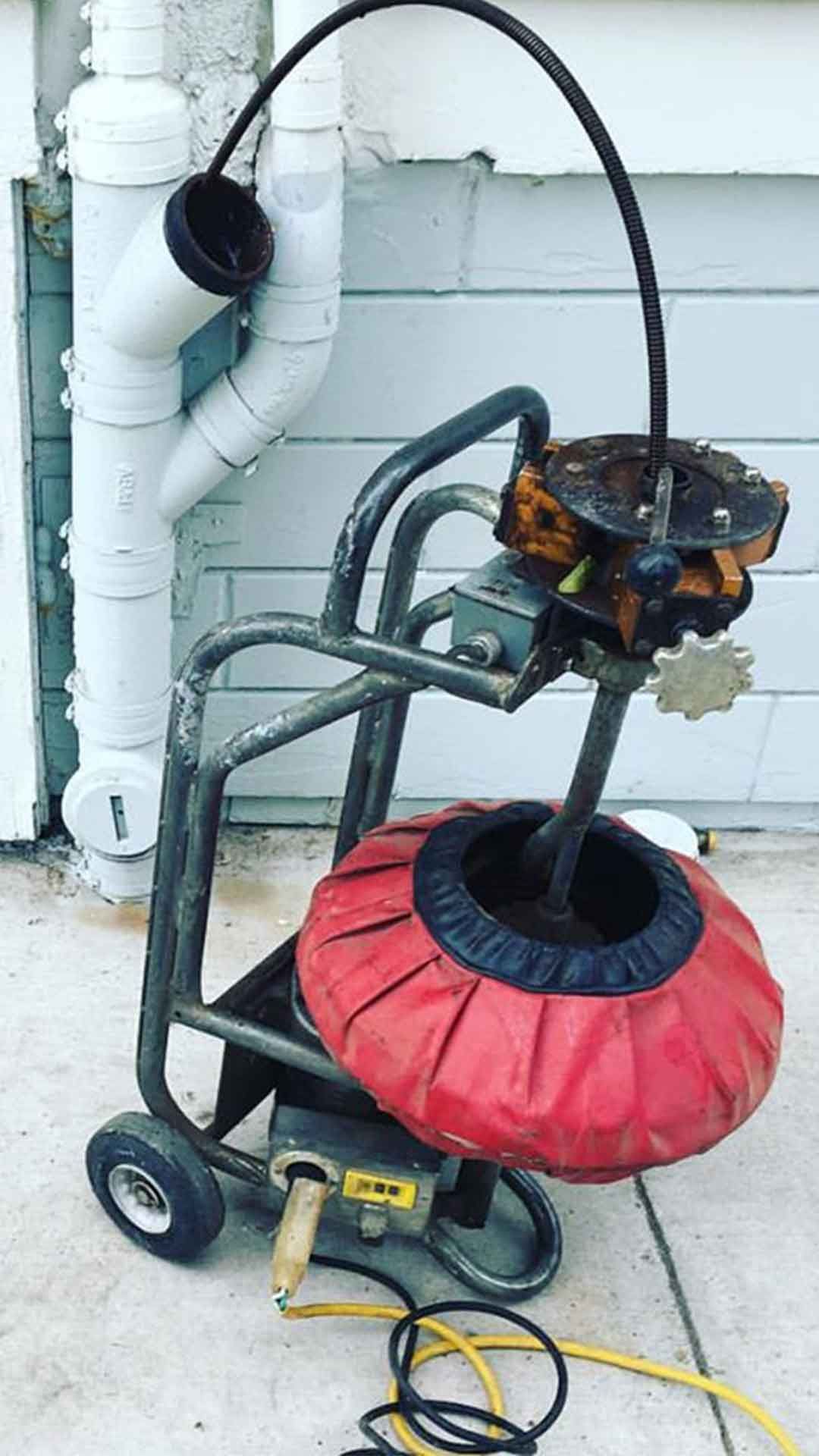 Ted & Bros Plumbing | drain cleaner is sitting on a cart next to a pipe.