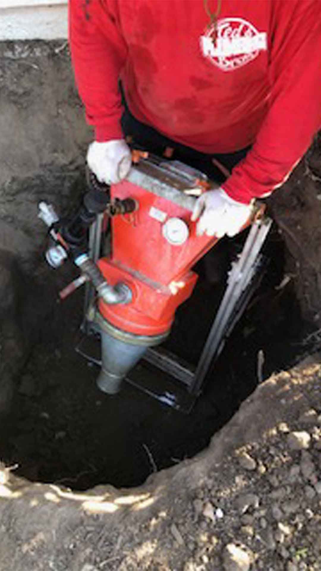 Ted & Bros Plumbing | man is using a machine to dig a hole in the ground.