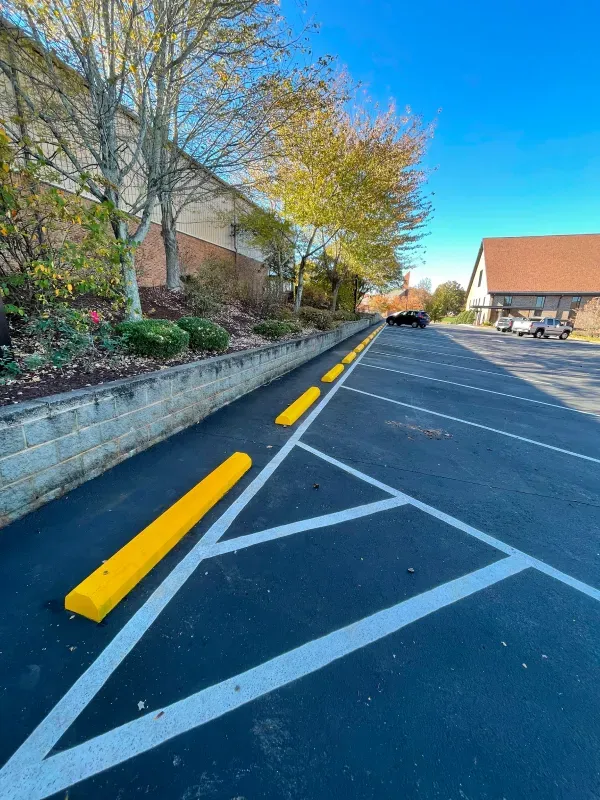 A parking lot with yellow curbs and a building in the background.