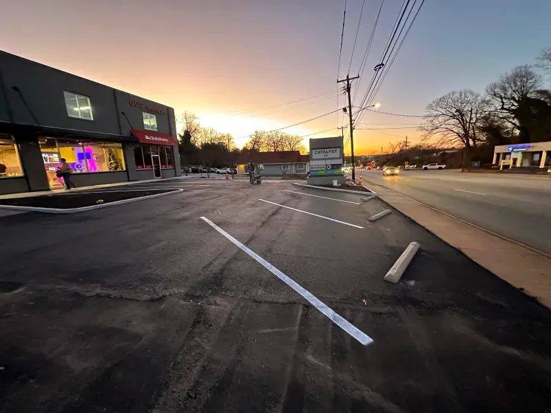 A parking lot in front of a building with a sunset in the background.
