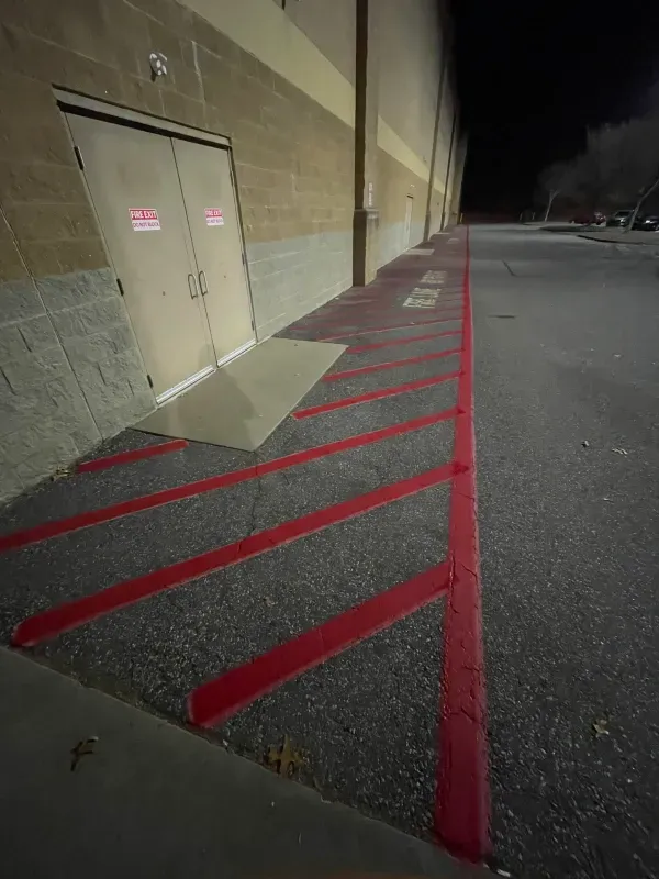 A parking lot with red lines painted on the side of it.