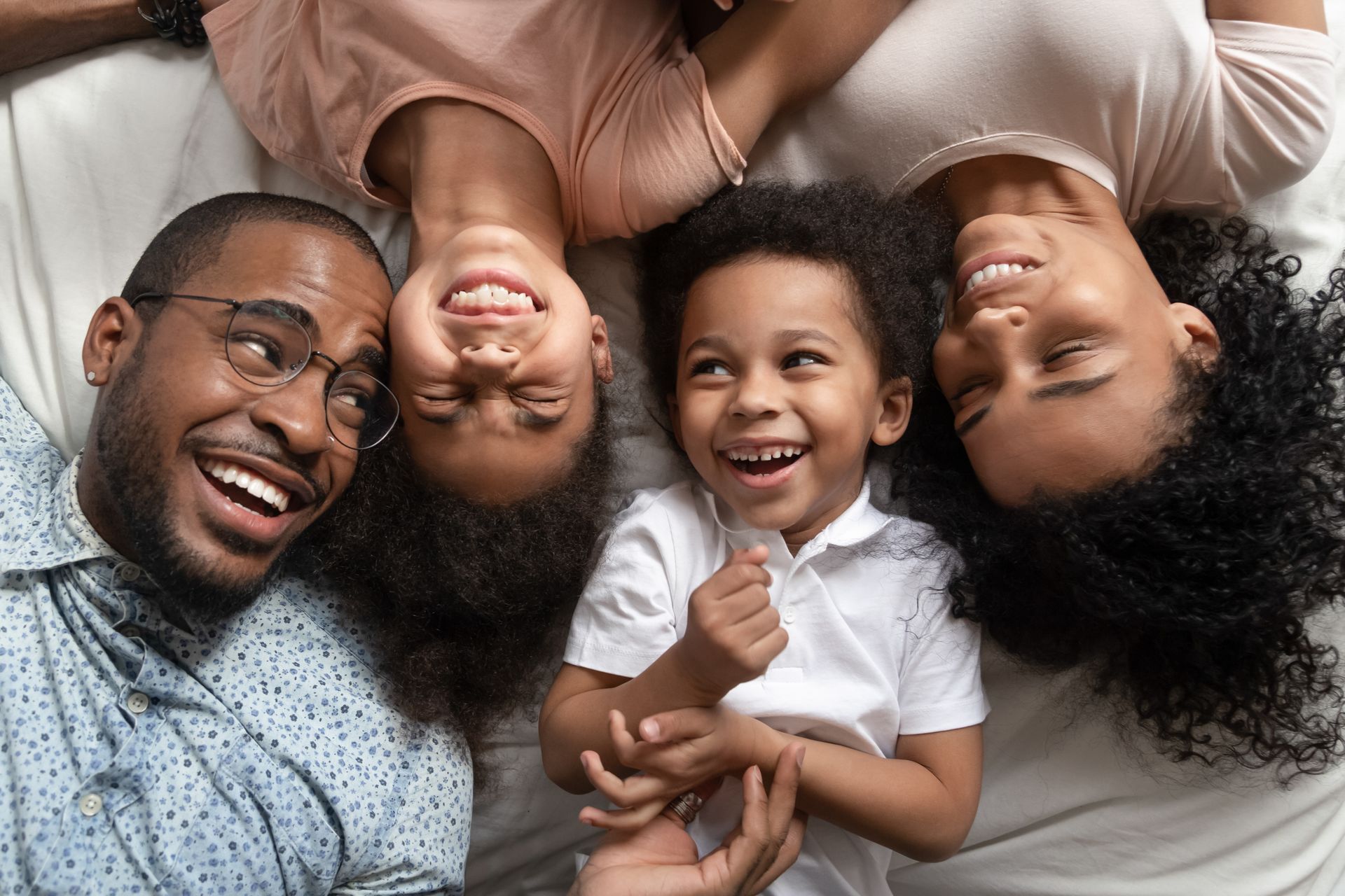 a family is laying on a bed together, smiling and laughing