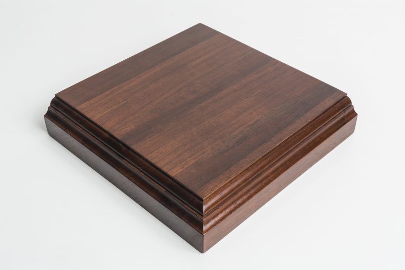 A square piece of wood is sitting on a white surface