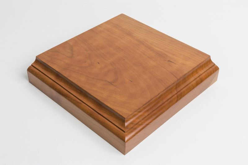 A square piece of wood is sitting on a white surface