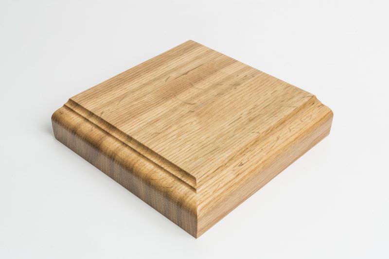 A square piece of wood is sitting on a white surface.
