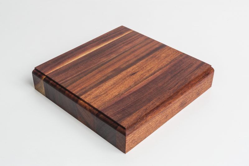 A square piece of wood is sitting on a white surface.