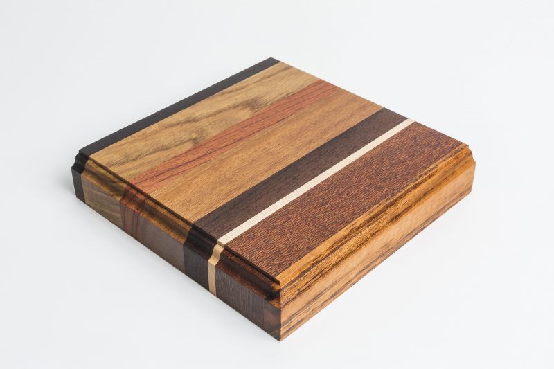 A wooden cutting board with a striped pattern is sitting on a white surface.