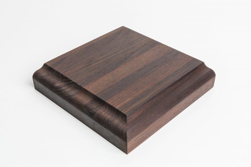 A square piece of wood is sitting on a white surface.