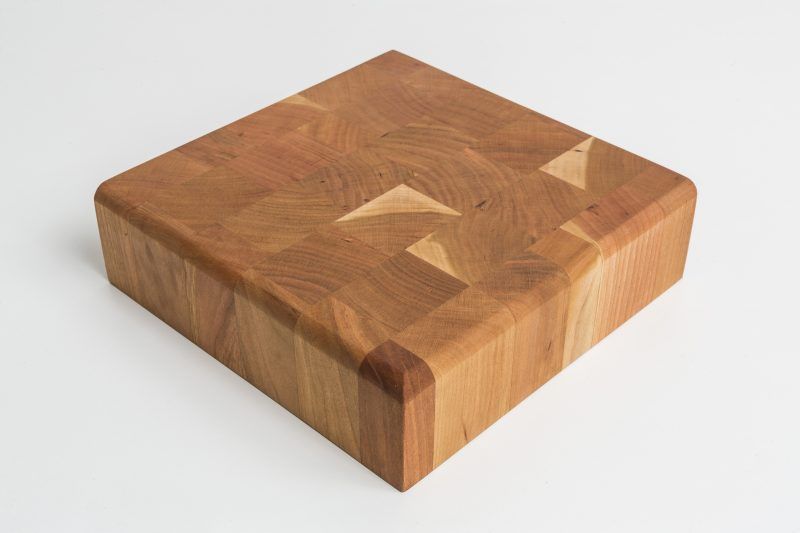 A wooden cutting board is sitting on a white surface.
