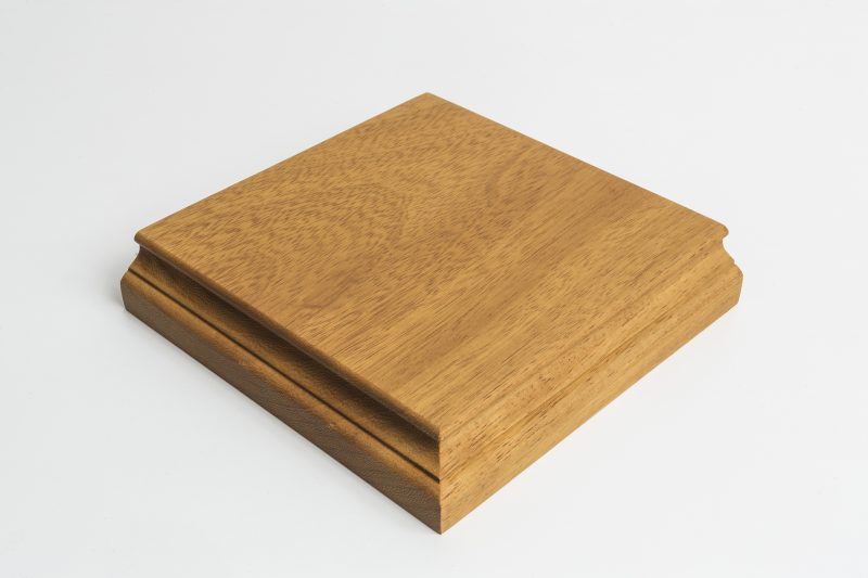 A square piece of wood is sitting on a white surface.