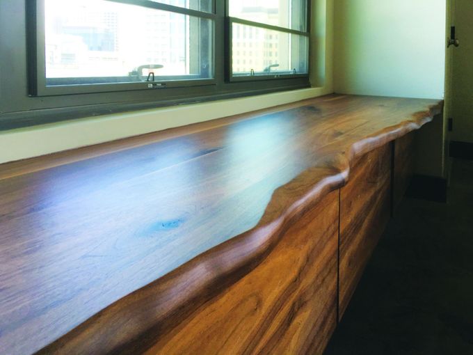 A wooden bench is sitting next to a window in a room.