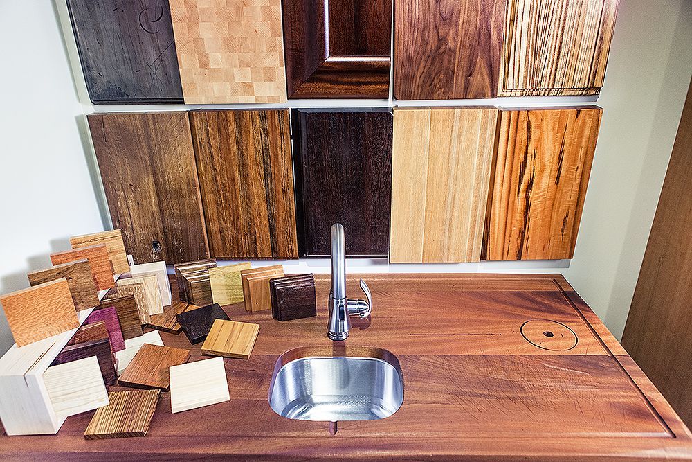 A sink is sitting on a wooden counter in front of a wall of wood samples.