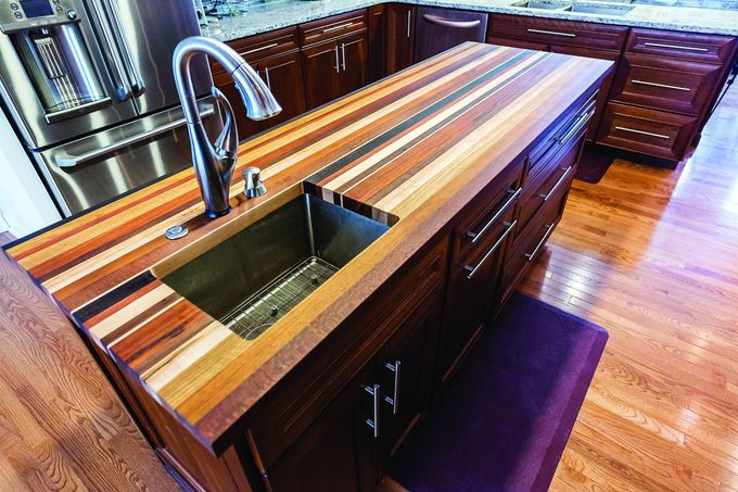 A kitchen with a wooden counter top and a stainless steel sink