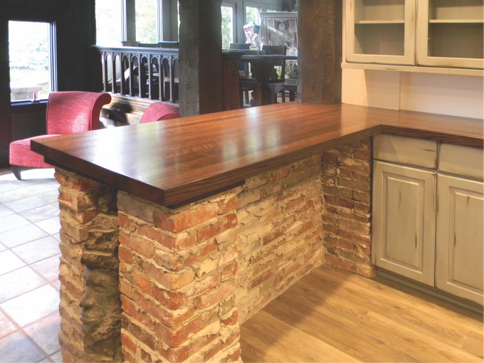 A kitchen with a wooden counter top and brick pillars
