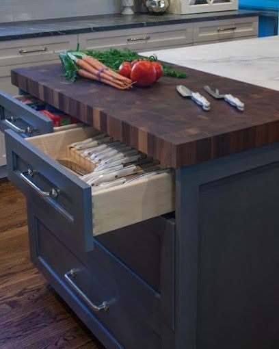 A kitchen island with a cutting board and drawers open