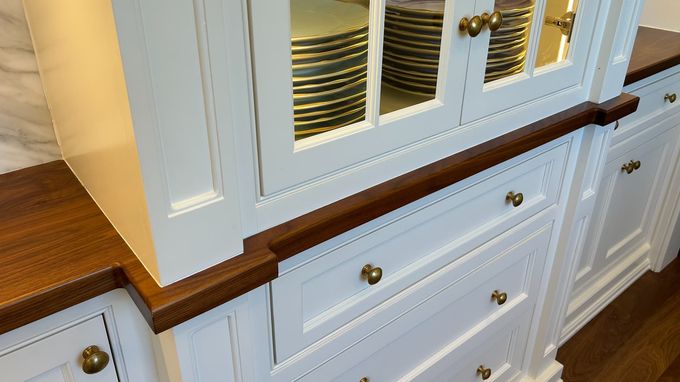 A kitchen with white cabinets and wooden counter tops filled with plates.