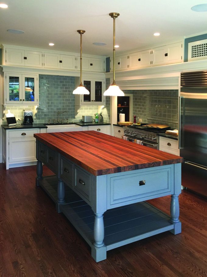 A kitchen with a large wooden island in the middle