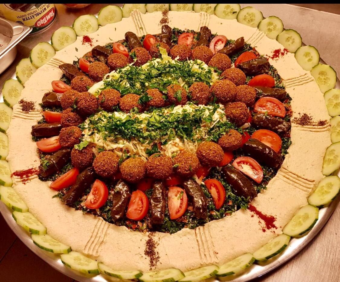 Falafel and stuffed grape leaves platter, with cucumbers, tomatoes, and parsley.