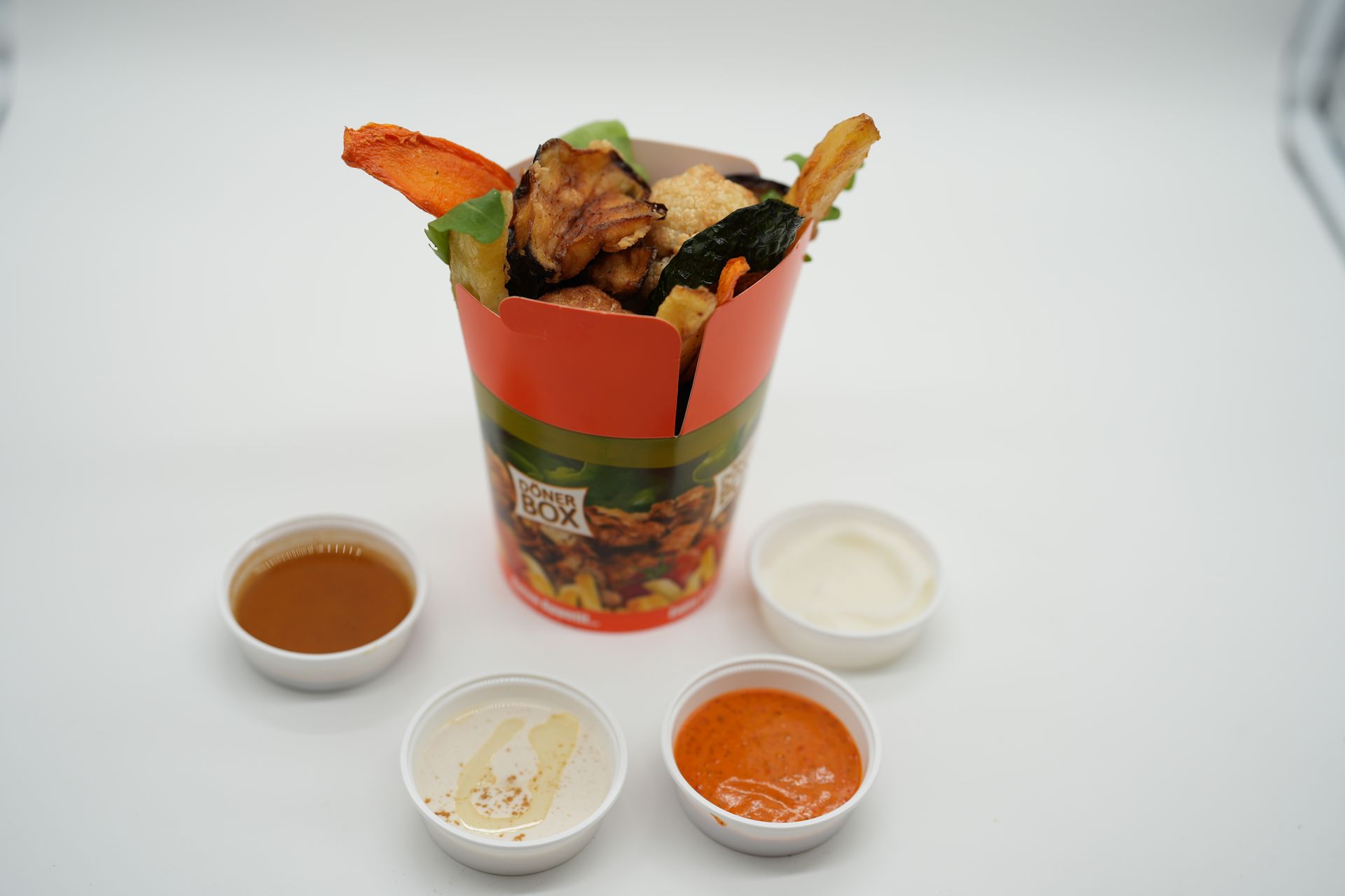 Fried food and assorted sauces in small containers, displayed on white surface.