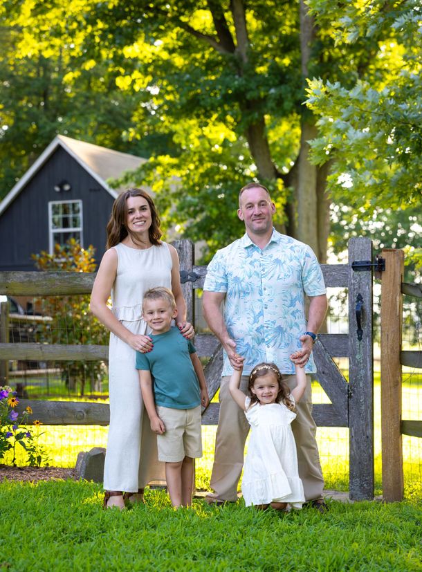 A man in blue overalls is standing in an office with his arms crossed