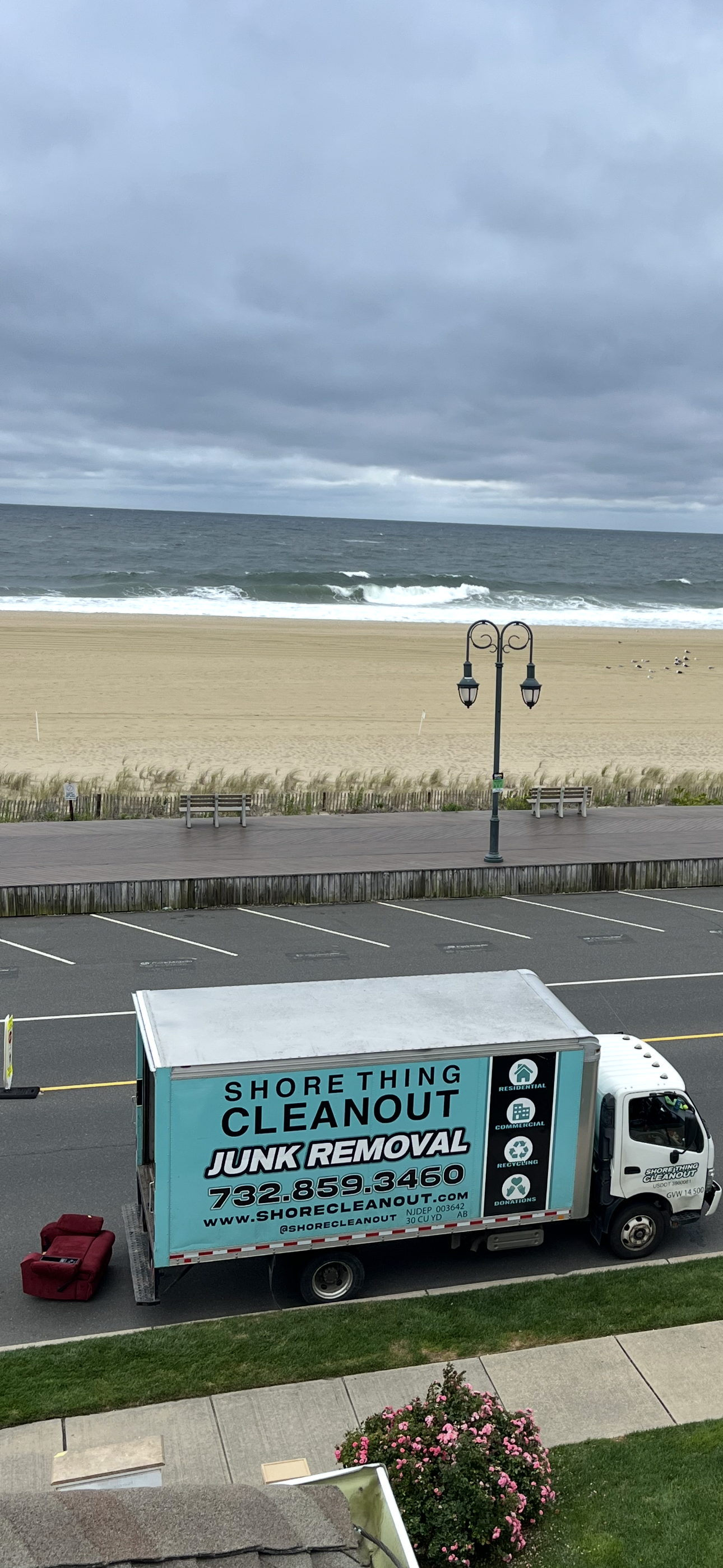 A box truck with "Everything Cleanout" on it parked near a beach with an overcast sky.