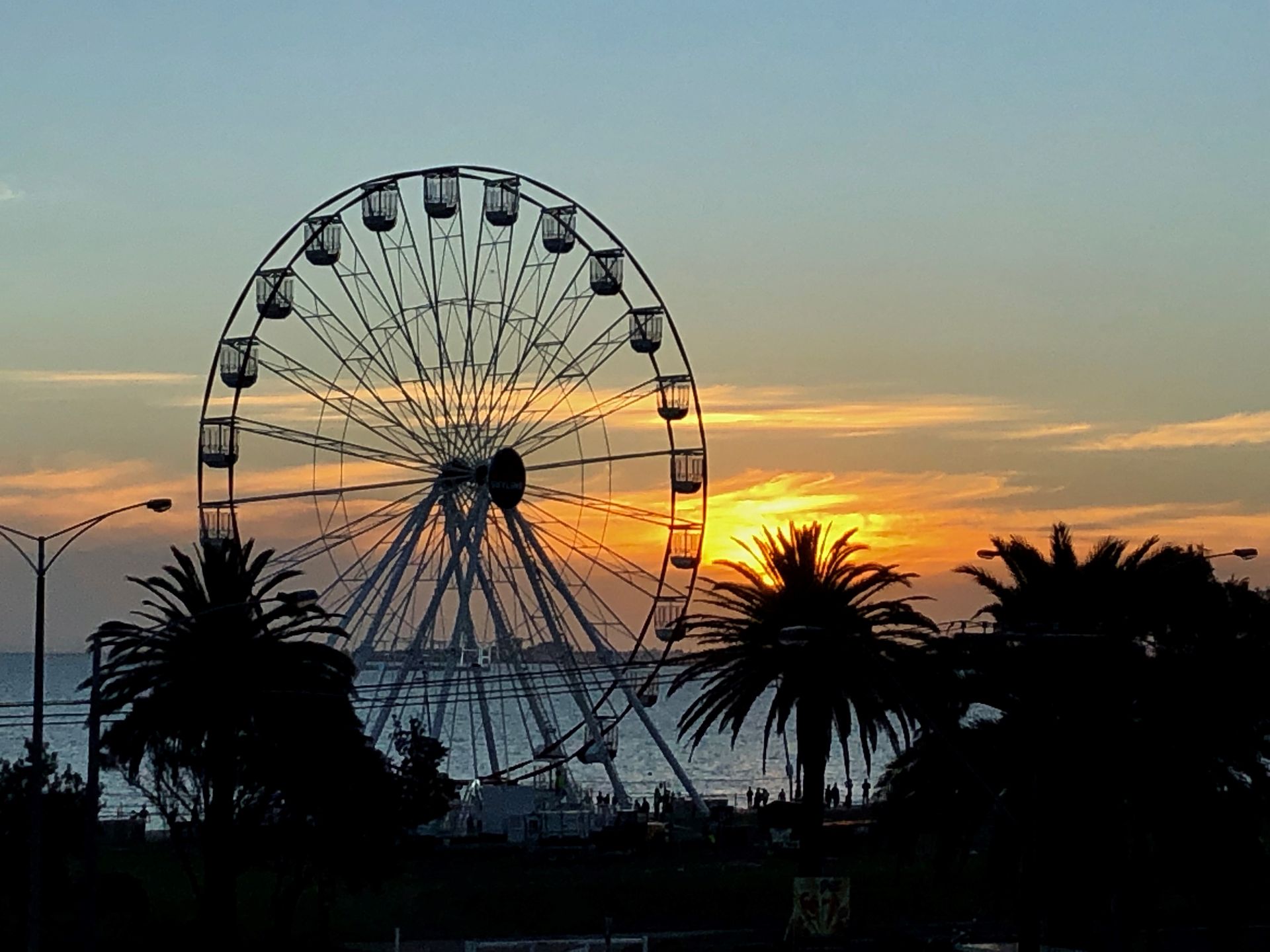a ferris wheel is silhouetted against a sunset sky